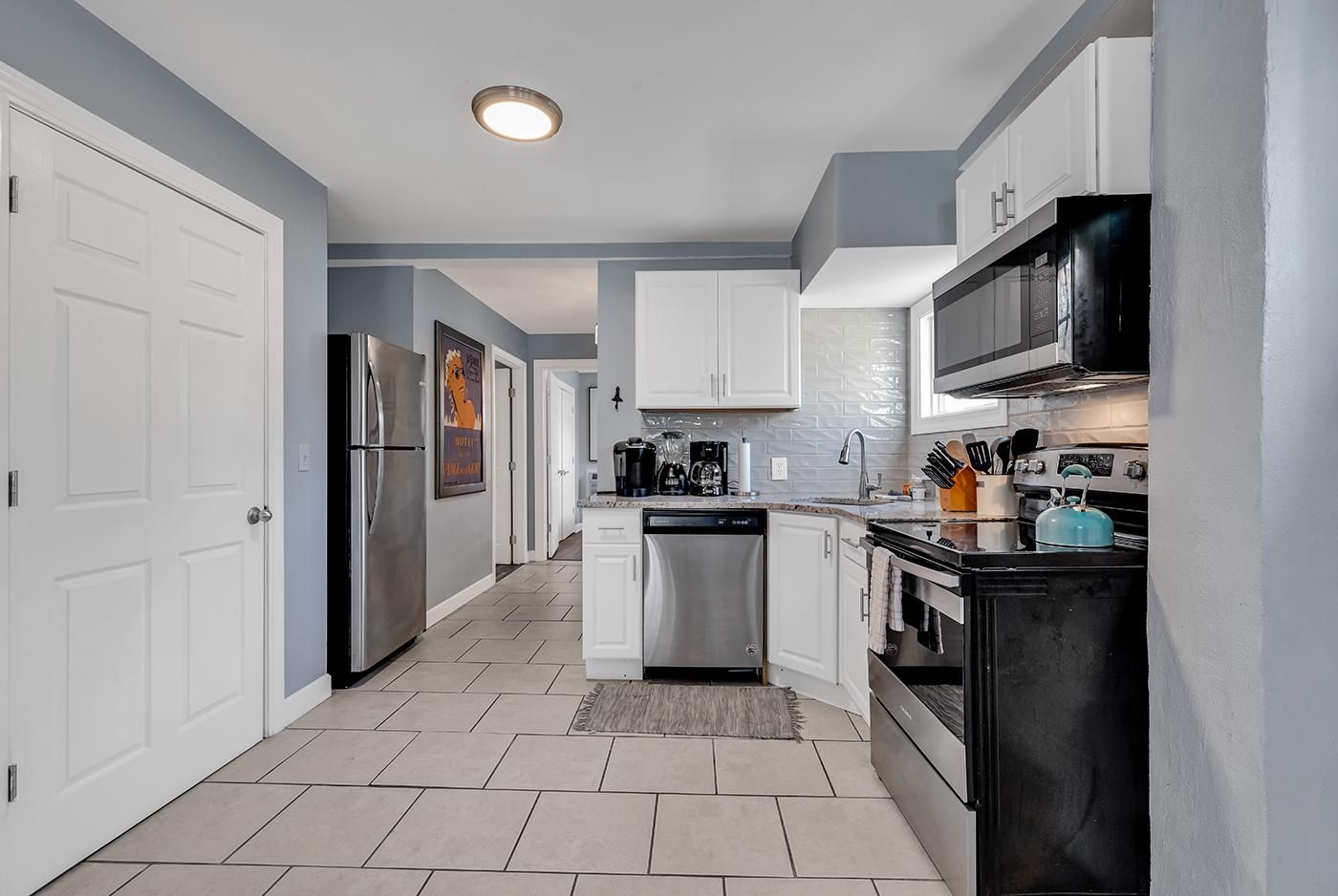 A modern kitchen with white cabinets, stainless steel appliances, and a tiled backsplash.