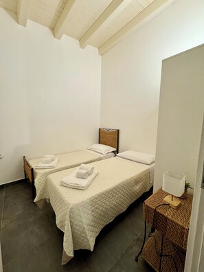 A small, clean room with two beds, a bedside table with a lamp, and a woven basket. - New Listing (Cinisi)