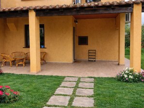 A covered patio area with a seating arrangement and a small garden.