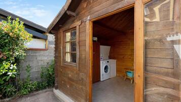 A wooden cabin with a laundry area, including a washing machine and a drying rack.