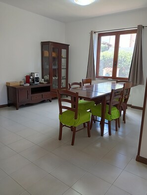 Un coin repas avec une table et des chaises en bois, un meuble avec des portes en verre et une fenêtre avec des rideaux.
