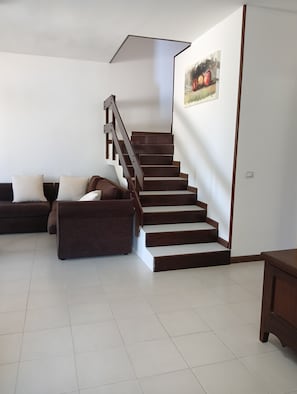 Ein Wohnzimmer mit Treppe, einer Couch und einem Gemälde an der Wand.