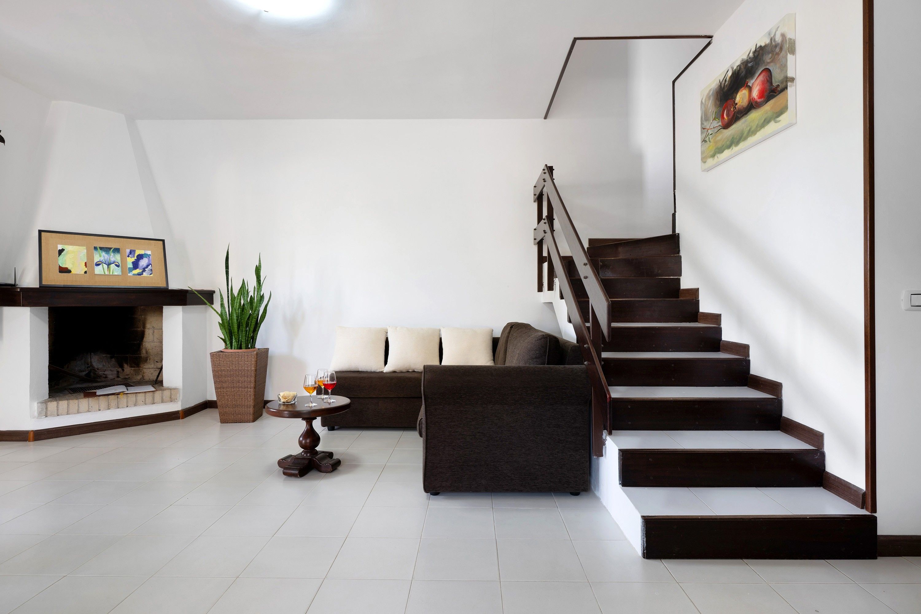 Ein modernes Wohnzimmer mit Kamin, einer Sofagarnitur, einem Esstisch mit Gläsern und einer Treppe.