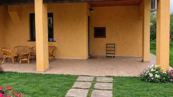 Uma área de varanda coberta, com assentos e um pequeno jardim.
