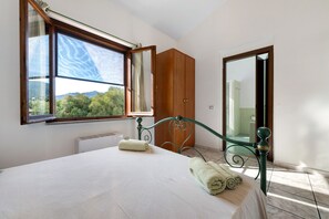 Un dormitorio con un ventanal grande, una cama, un radiador y un armario.