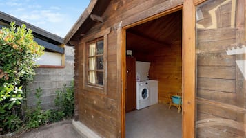 Een houten chalet met een ruimte voor het wasgoed, inclusief een wasmachine en een droogrek.