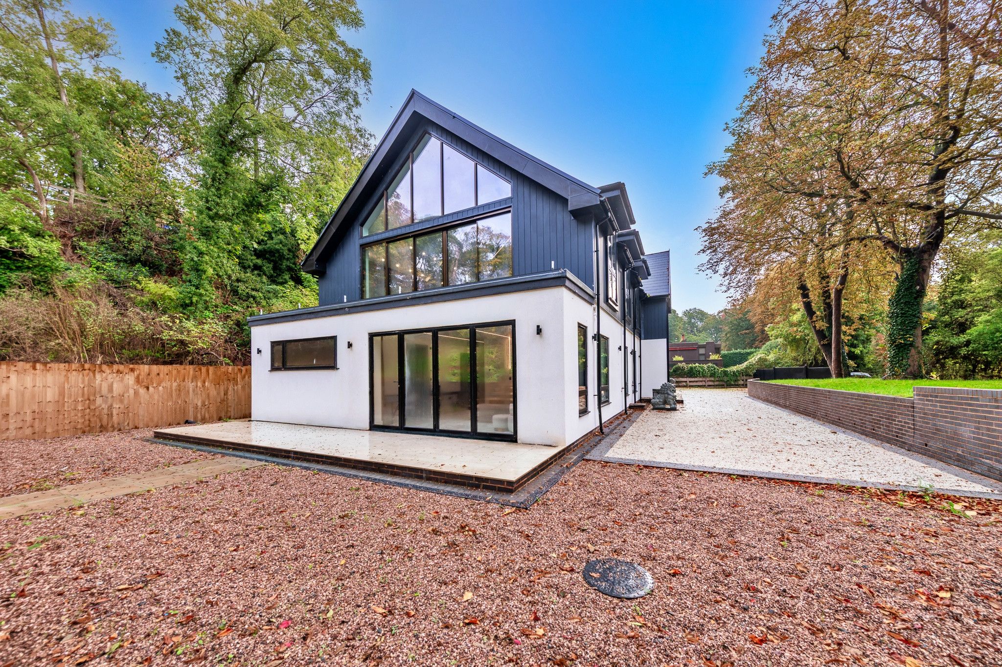 A modern two-story house with large windows and a covered patio area.