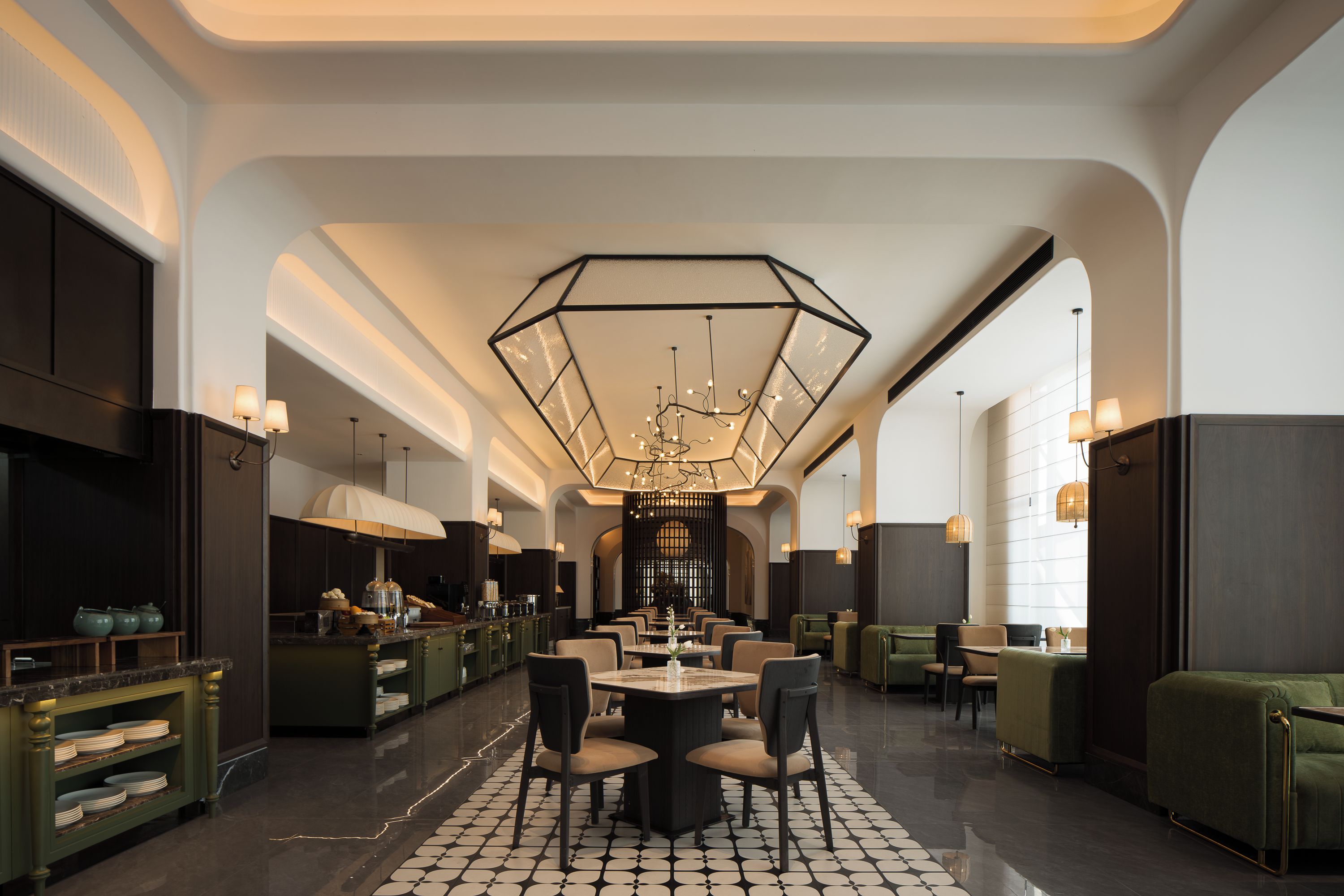 A spacious hotel lobby with a central dining area, multiple seating options, and a modern chandelier.
