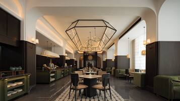 A spacious hotel lobby with a central dining area, multiple seating options, and a modern chandelier.