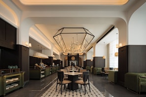 A spacious hotel lobby with a central dining area, multiple seating options, and a modern chandelier. - Mangrove Hotel (Vientiane)