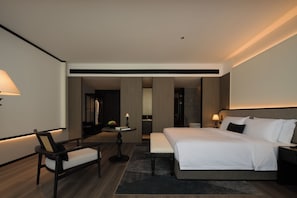 A modern hotel room with a large bed, a desk, a chair, and a small table with a candle. - Mangrove Hotel (Vientiane)