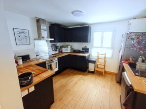 Une cuisine compacte dotée de plans de travail en bois, d’un four encastré, d’un four à micro-ondes et d’un réfrigérateur.