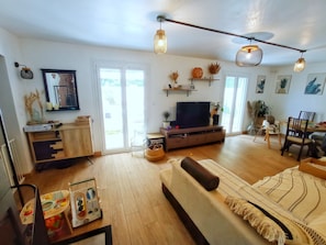 Un salon bien éclairé, avec un canapé, un téléviseur et un plancher en bois.