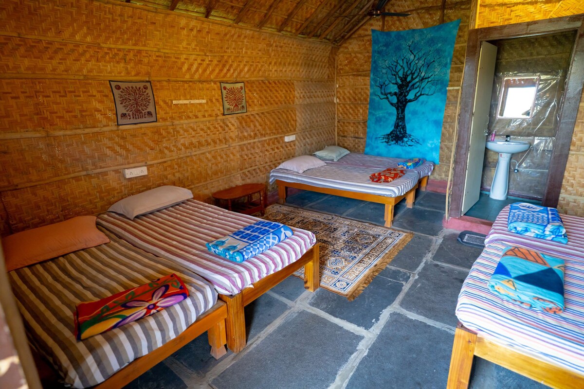 A room with two wooden beds, a bathroom with a sink, and a large tapestry on the wall.
