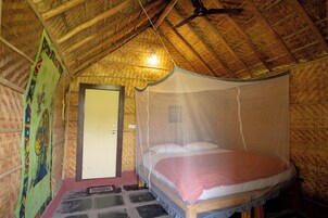 Una habitación con una cama bajo una mosquitera, una puerta y techo de madera.
