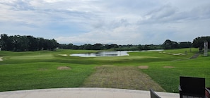 Um campo de golfe com lago, árvores e mastro.