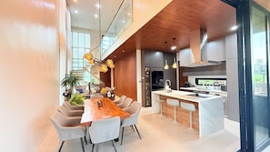 Cozinha moderna com ilha central, banquetas e iluminação pendente.