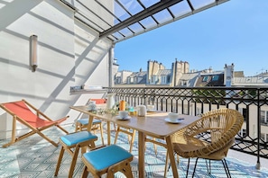 Ein Balkon mit Tisch, Stühlen und Blick auf die Stadt.