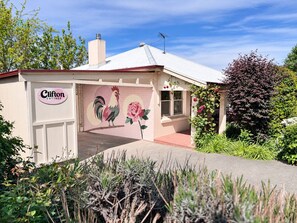 Una cabaña con un mural de gallo, una chimenea y un jardín.