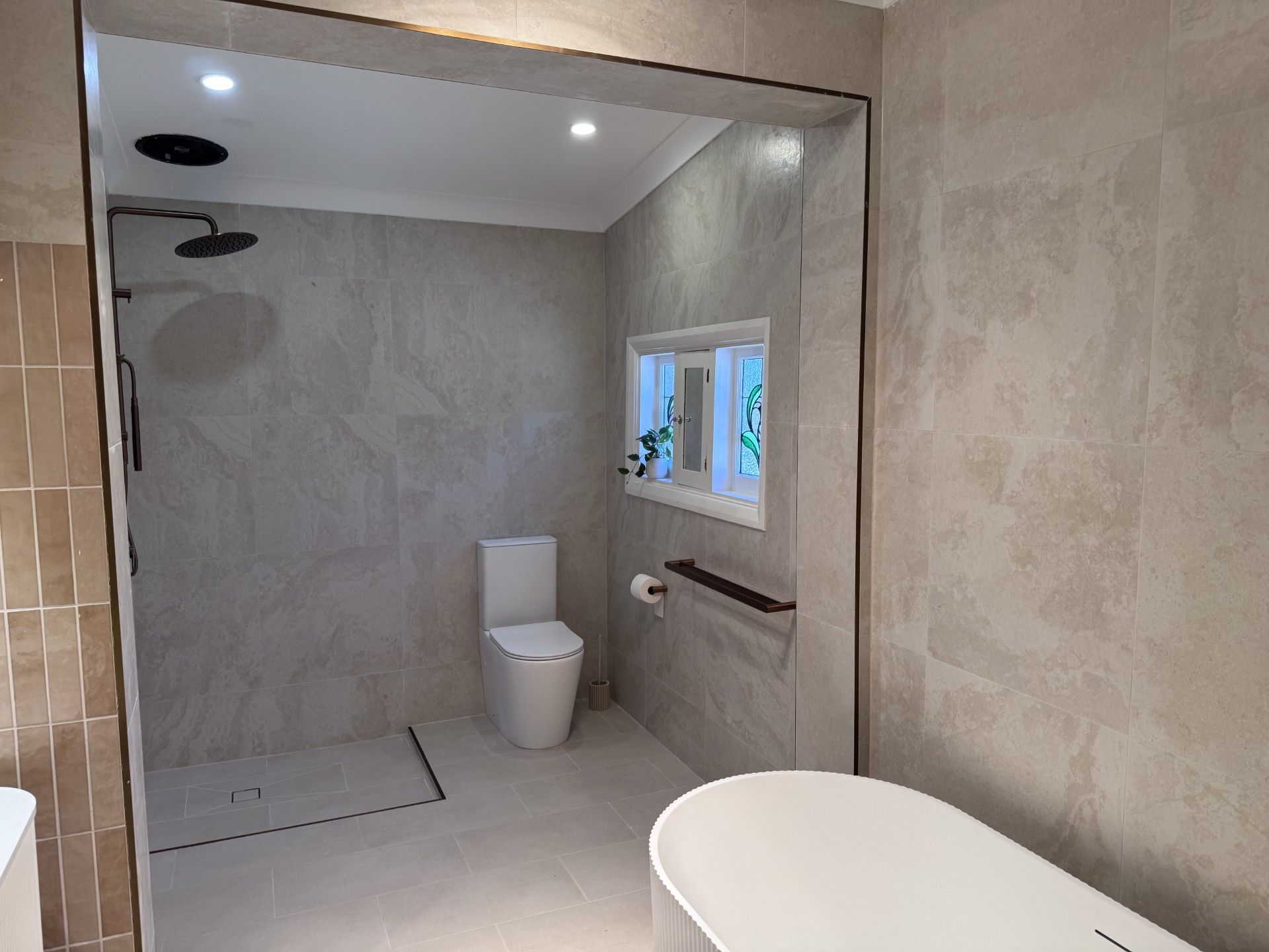 A bathroom with a shower, toilet, and a window with a view.
