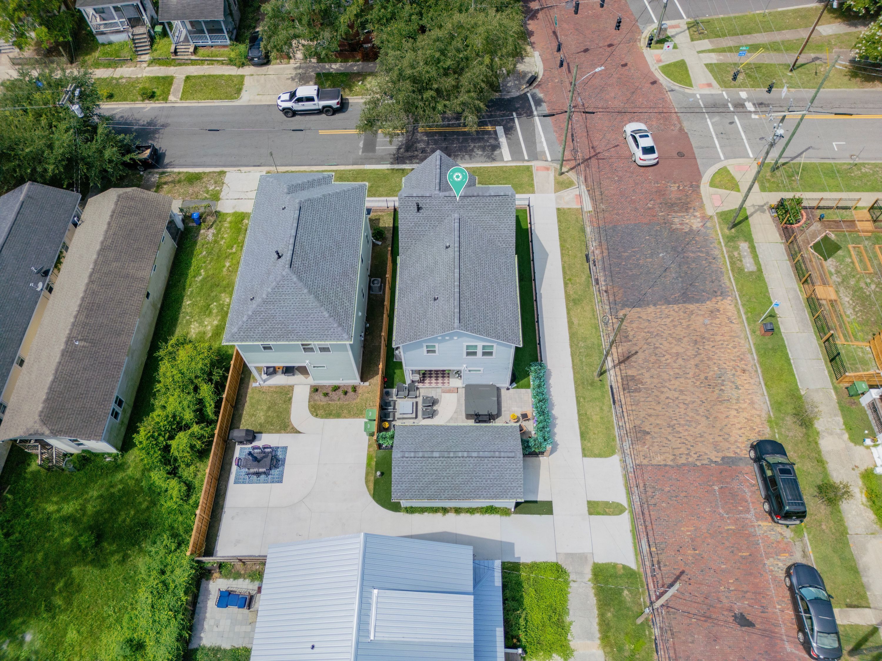 Vista aérea de um bairro residencial com casas, uma rua e carros estacionados.