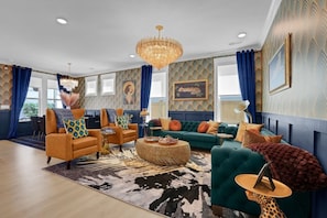 A spacious living room with a chandelier, sofas, and a patterned rug. - The Savoy Art Deco Luxury Hot Tub (Wilmington)