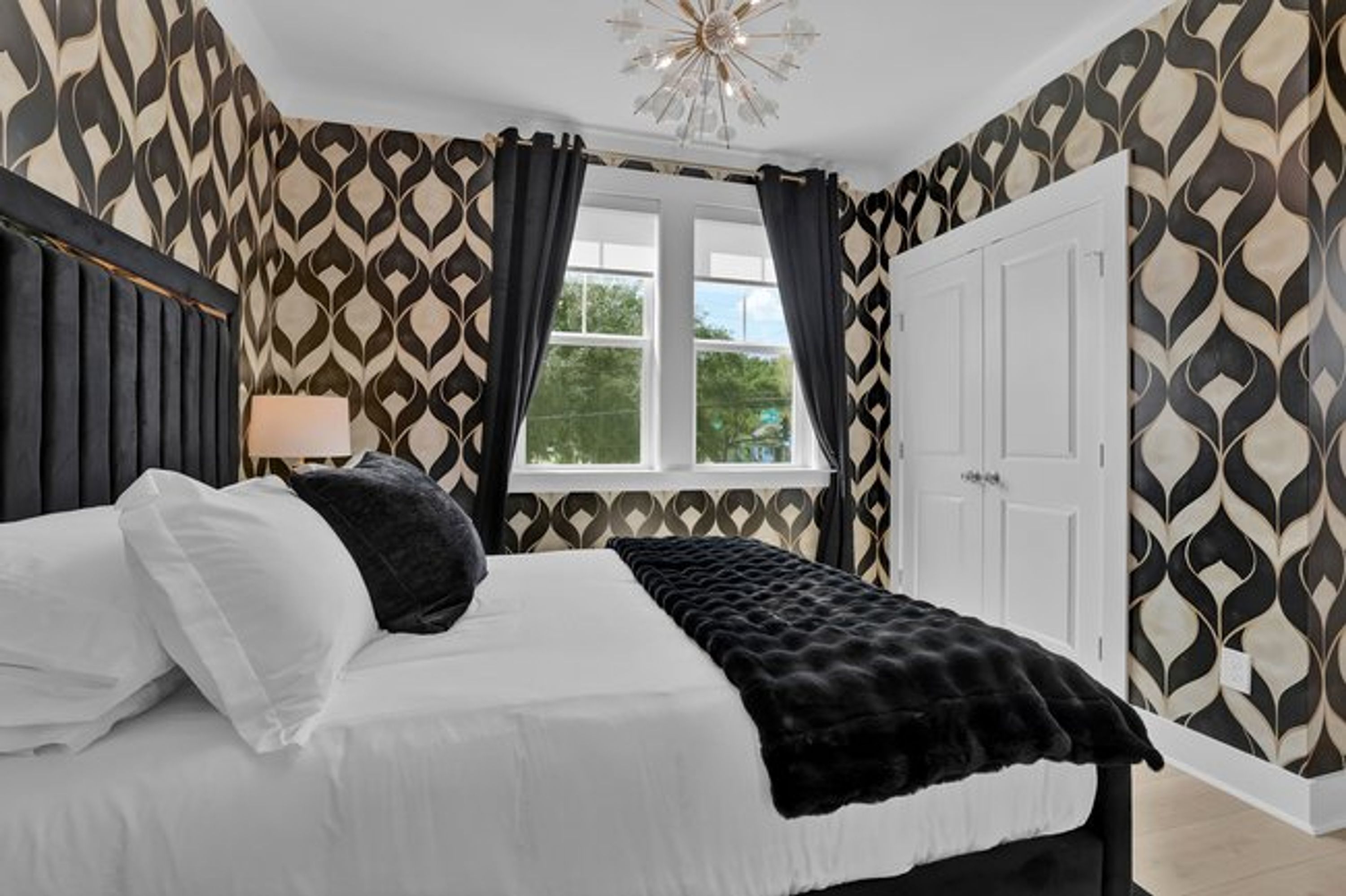 A bedroom with a bed, a window, and patterned wallpaper.