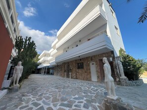 A multi-story building with a stone facade and a paved courtyard. - EO Rodou Lindou 407 (Faliraki)