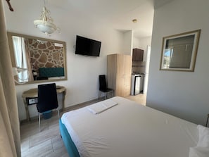 A hotel room with a bed, a desk with a chair, a television, a wardrobe, and a kitchenette. - EO Rodou Lindou 407 (Faliraki)