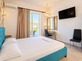 Habitación de hotel con cama, escritorio, silla, televisor y vista al exterior.