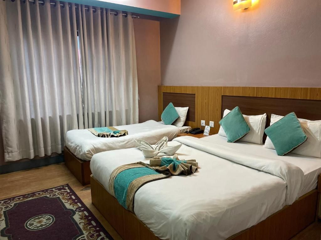 A hotel room with two beds, a wooden headboard, a window with white curtains, and a wall-mounted light fixture.