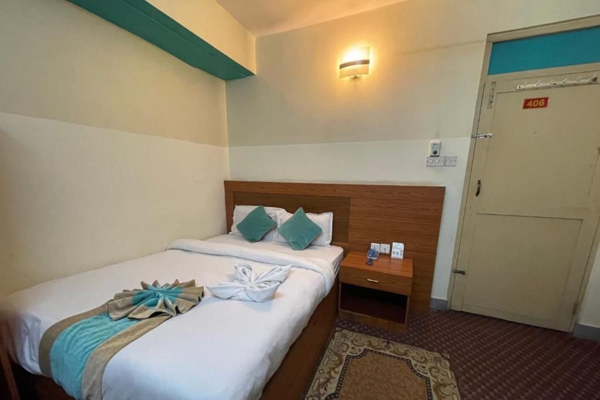 A hotel room with a bed, bedside table, and a door marked with the number 406.
