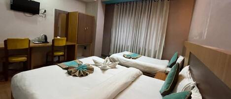 A hotel room with two beds, a desk with a chair, a wardrobe, and a television on the wall.