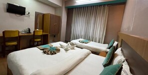 A hotel room with two beds, a desk with a chair, a wardrobe, and a television on the wall. - Hotel The President (Kathmandu)