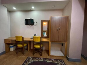 A small room with a desk, two chairs, a television mounted on the wall, and a wardrobe. - Hotel The President (Kathmandu)