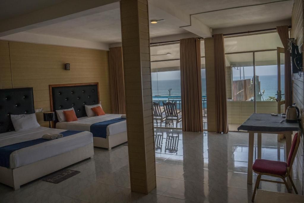 Habitación de hotel con dos camas, un balcón con vistas y un área de comedor.