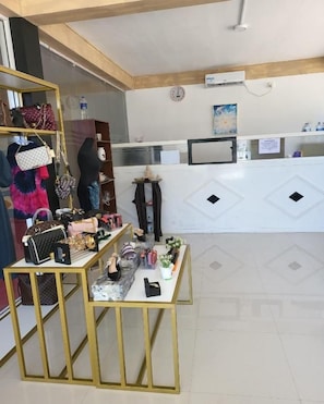 Una zona de recepción con mostrador, una exhibición de bolsos y una pequeña mesa con objetos.
