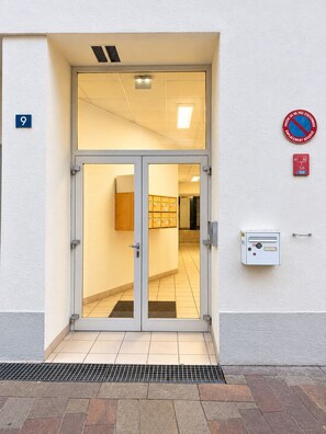 Entrada d'un edifici amb una porta doble, una ranura per correu i un detector de fum.