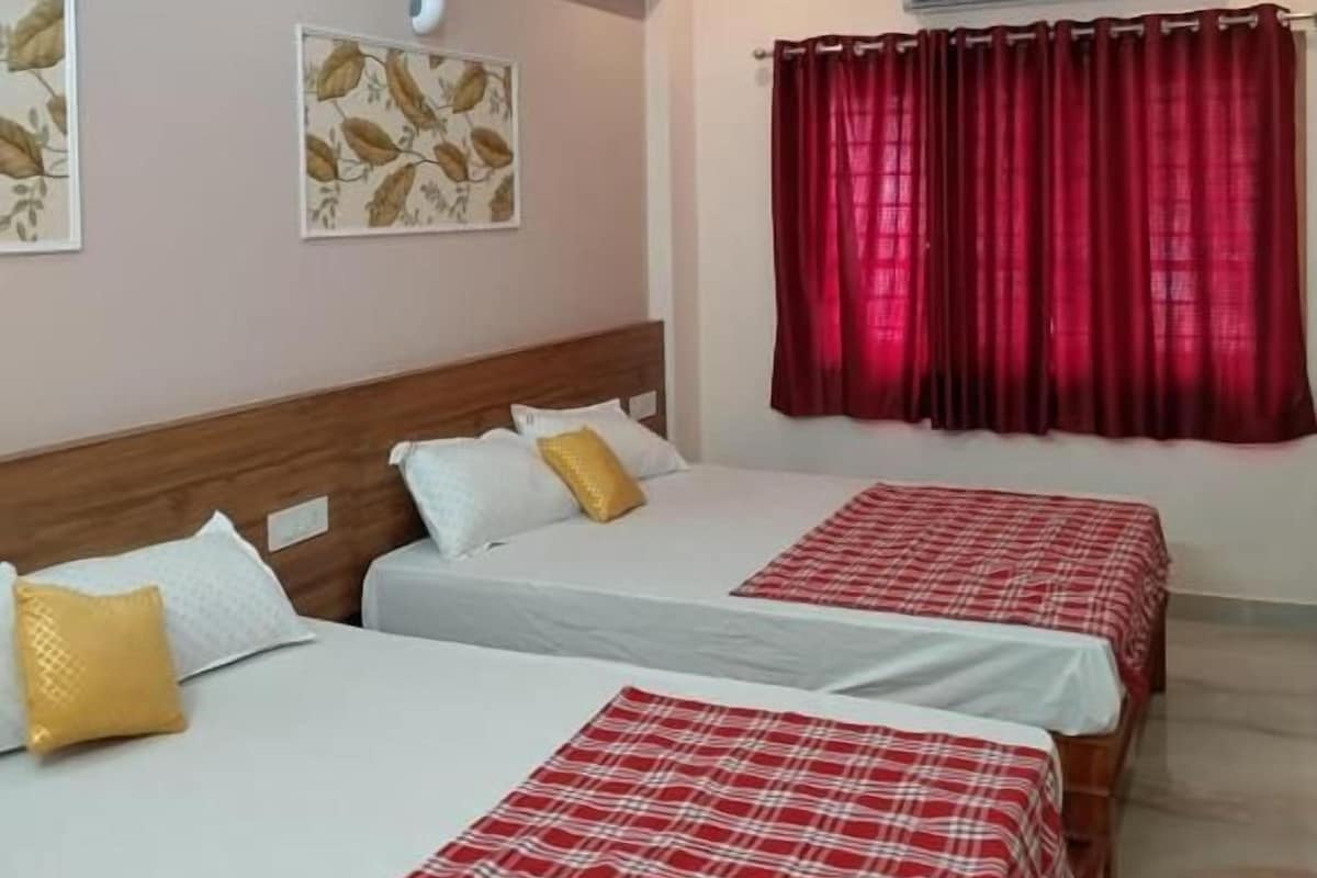 Una habitación de hotel con dos camas, ventiladores de techo, una cortina roja y obras de arte en la pared.