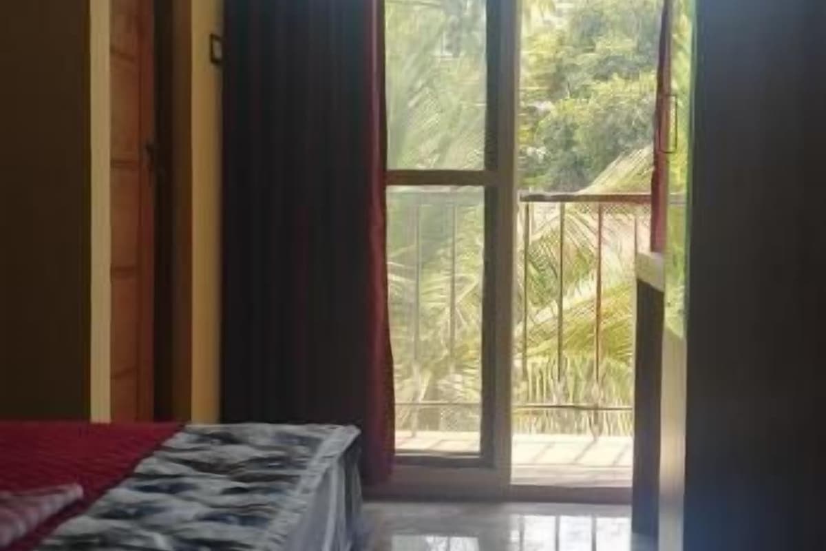 Una habitación con cama, puerta corrediza al balcón y vistas a zonas verdes.