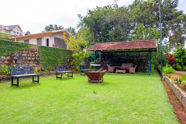 A well-maintained garden with a stone wall, a covered seating area, and outdoor furniture.