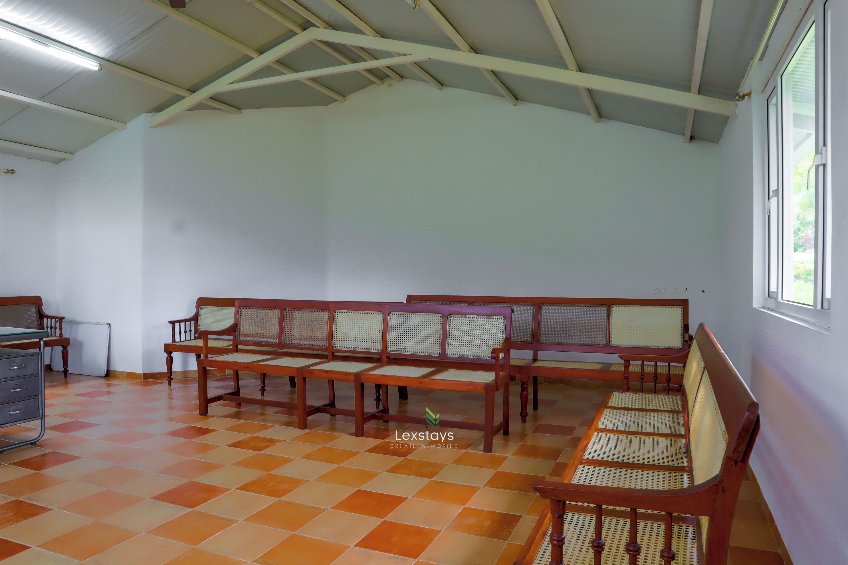 Una habitación con techos altos, suelo de cuadros y un rincón de estar con muebles de madera.