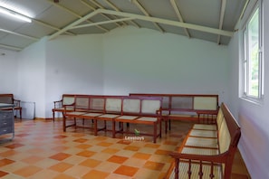 A room with a high ceiling, a checkered floor, and a seating area with wooden furniture. - 42 Green Pastures Tea Estate Experience (Araihatty)