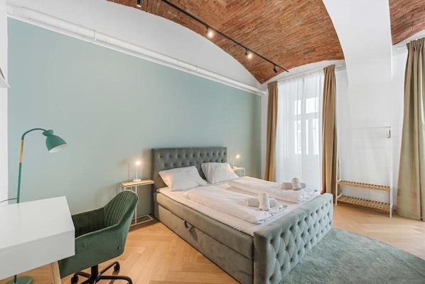 Un dormitorio con una cama grande, un escritorio, una silla y una ventana con cortinas.