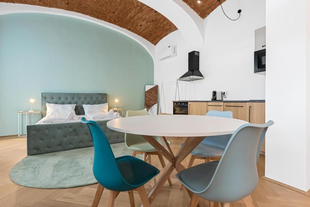 A modern interior with a round dining table, chairs, a sofa, and a kitchen area.
