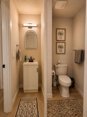 Ein Badezimmer mit Toilette, Waschbecken und Spiegel. An der Wand hängen zwei Bilder in Rahmen.