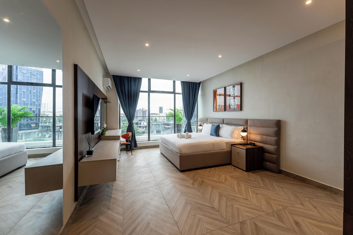 Quarto de hotel moderno com uma cama grande, uma escrivaninha e uma TV.