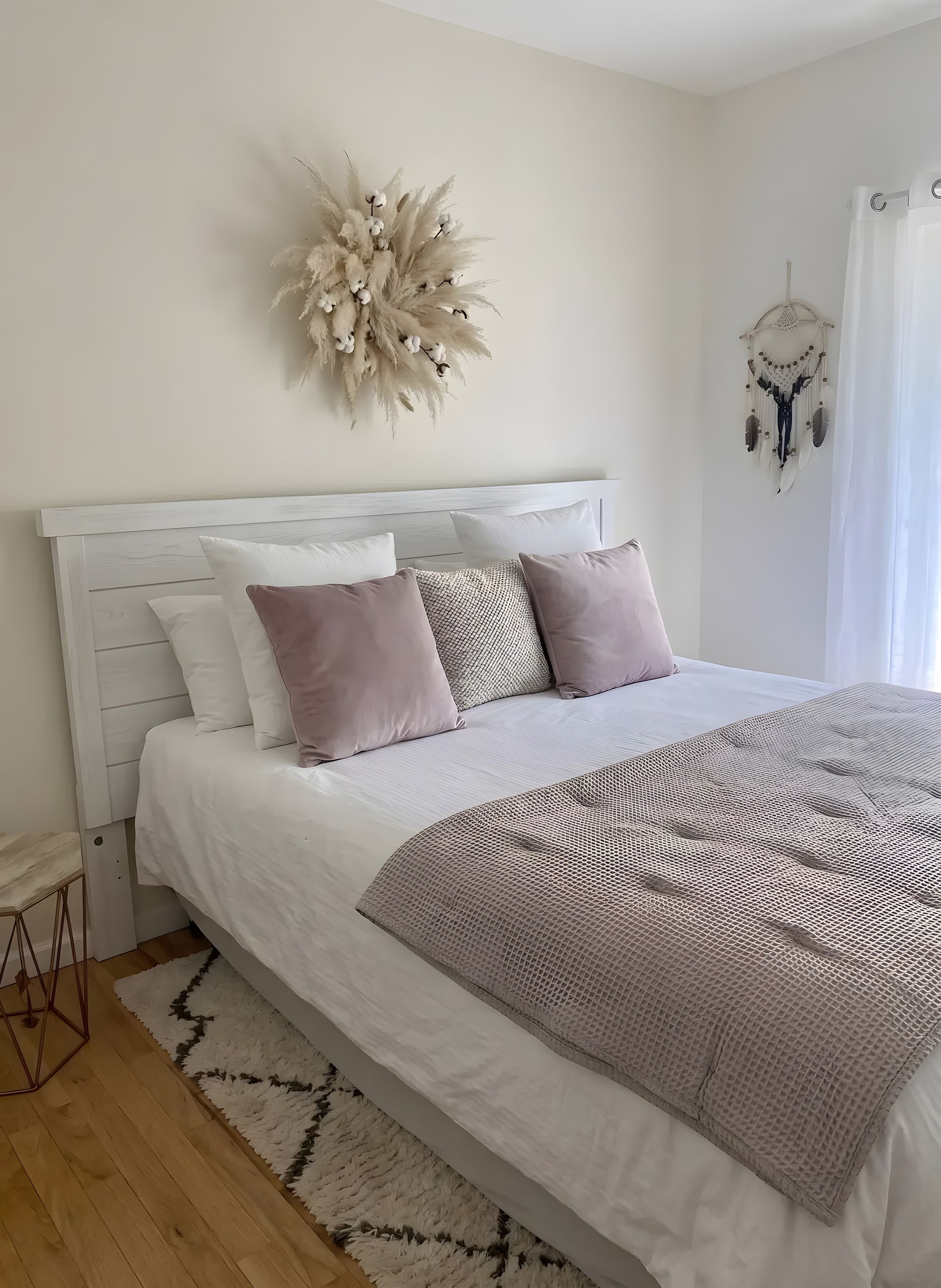 A neatly made bed with a white headboard, a patterned throw blanket, and a decorative wall hanging.