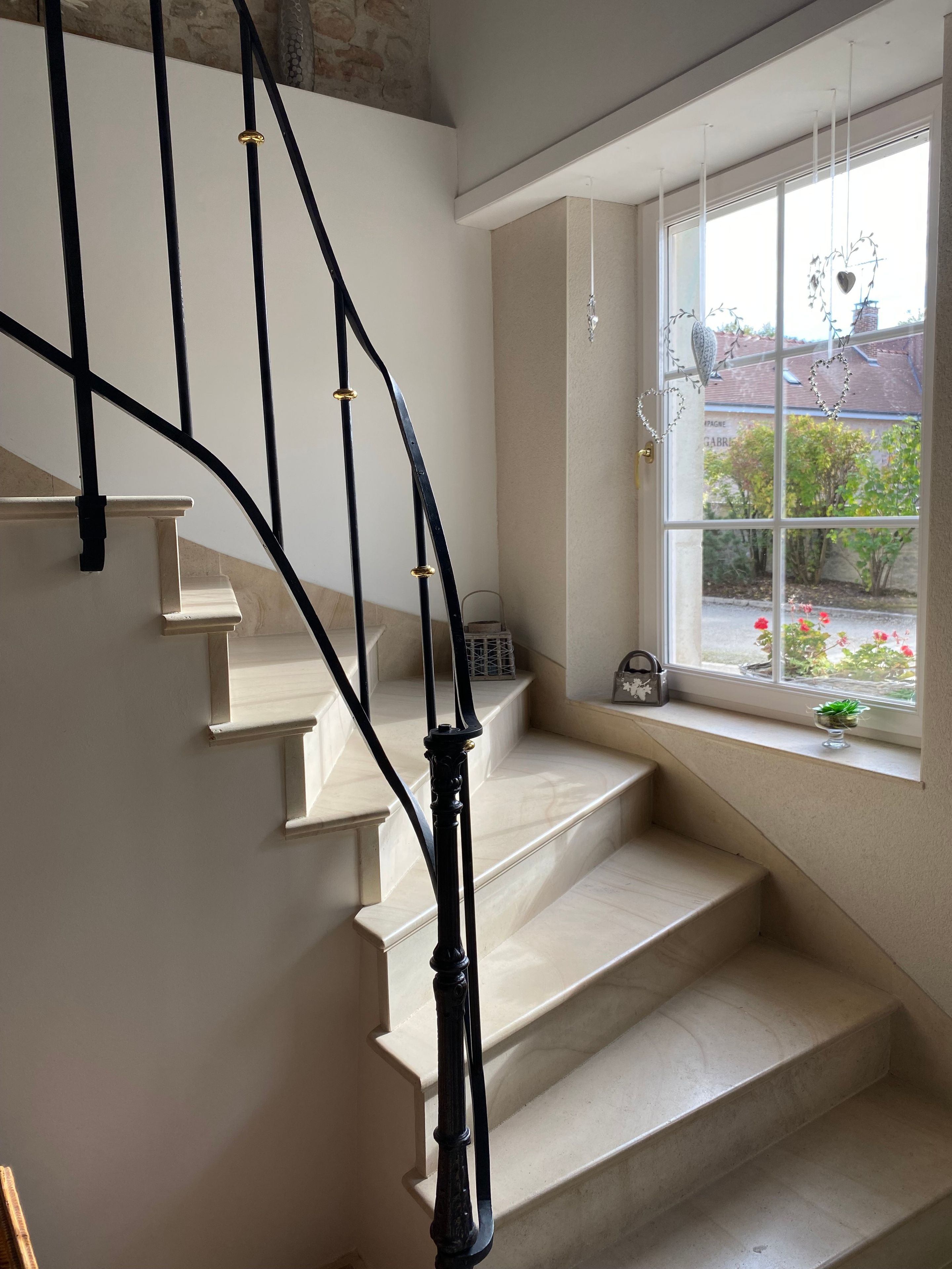 Un escalier avec une rampe en métal noir et des marches de couleur beige.