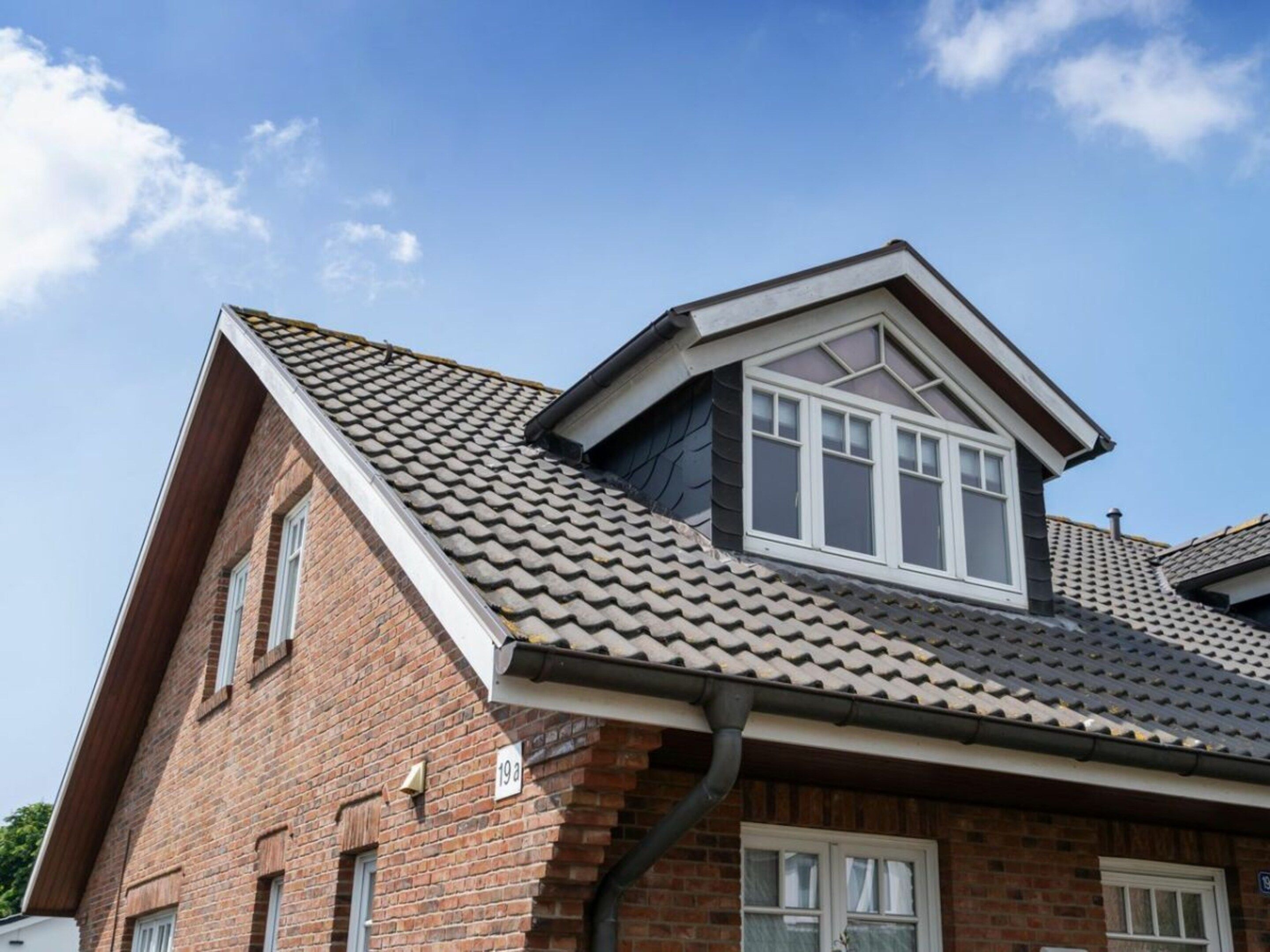 A two-story brick house with a gabled roof and dormer windows.